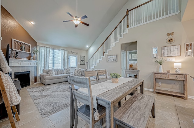 tiled dining area featuring ceiling fan, a fireplace, and high vaulted ceiling