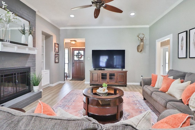 living room featuring light hardwood / wood-style floors, a brick fireplace, ceiling fan, and ornamental molding