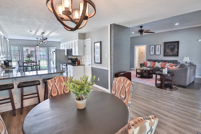 dining room with ceiling fan with notable chandelier, wood-type flooring, and sink