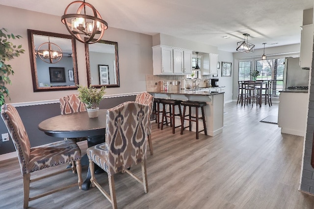 dining room with sink, light hardwood / wood-style flooring, and a notable chandelier