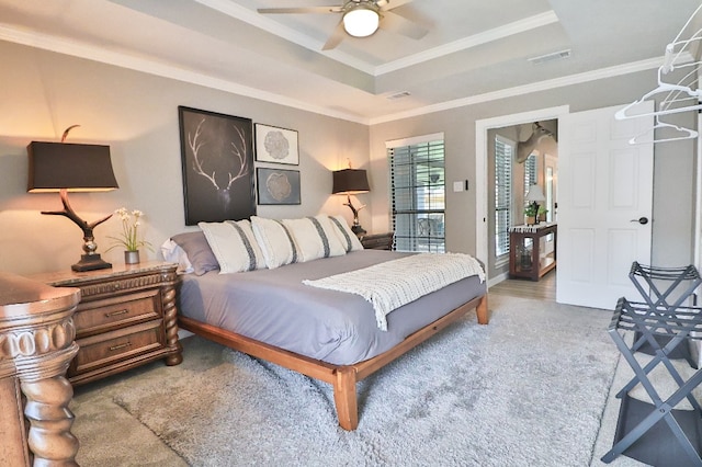 bedroom with ceiling fan, a raised ceiling, crown molding, and light hardwood / wood-style flooring