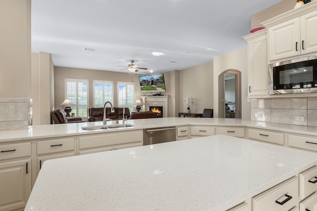 kitchen featuring kitchen peninsula, appliances with stainless steel finishes, tasteful backsplash, ceiling fan, and sink