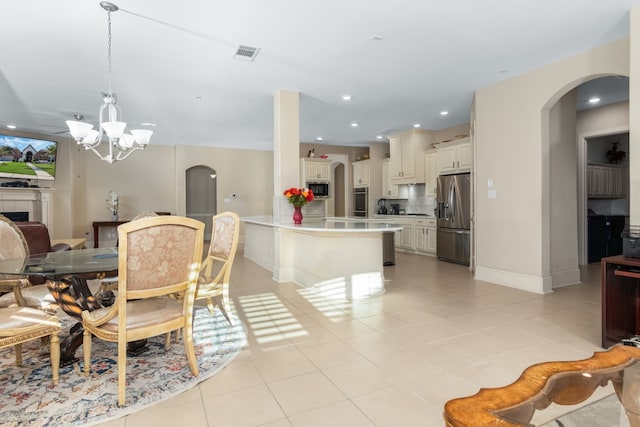 tiled dining area featuring a tiled fireplace and a notable chandelier