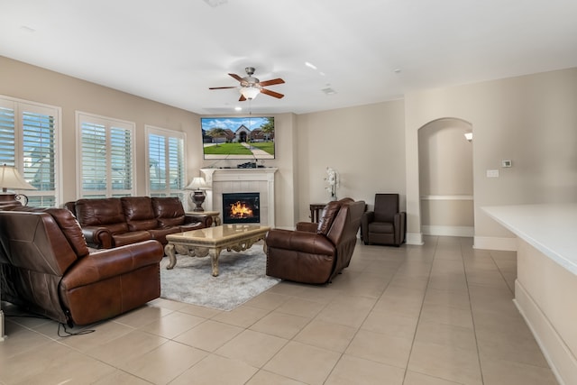 tiled living room featuring ceiling fan and a fireplace