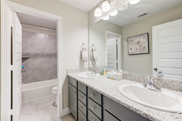 full bathroom with tile patterned floors, vanity, tiled shower / bath combo, and toilet