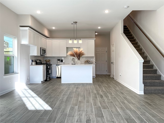 kitchen featuring pendant lighting, a center island, white cabinets, light wood-type flooring, and stainless steel appliances