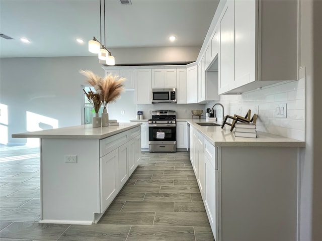 kitchen featuring stainless steel appliances, a healthy amount of sunlight, sink, decorative light fixtures, and white cabinetry