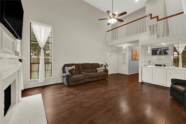 living room featuring ceiling fan, dark wood-type flooring, high vaulted ceiling, and a brick fireplace