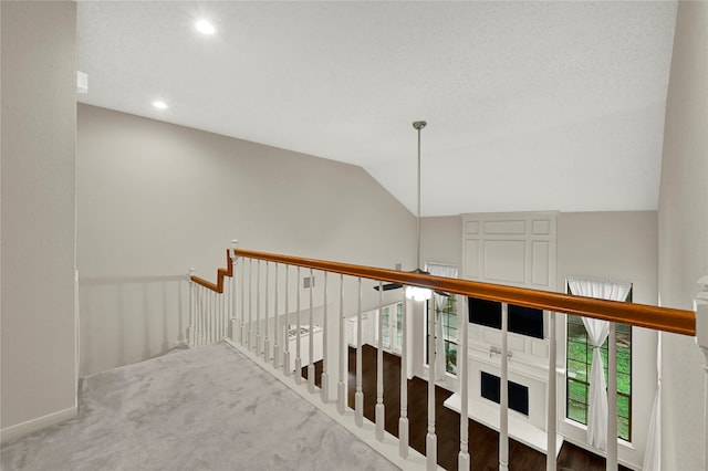 hallway with carpet floors and lofted ceiling