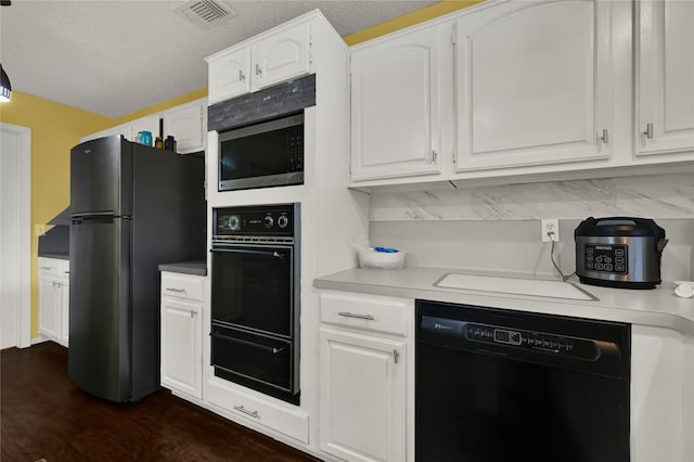 kitchen featuring a textured ceiling, white cabinets, black appliances, and dark hardwood / wood-style floors