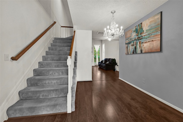 staircase featuring a notable chandelier, a textured ceiling, and hardwood / wood-style flooring