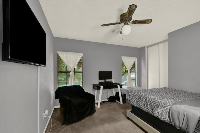 carpeted bedroom featuring multiple windows, ceiling fan, and a textured ceiling