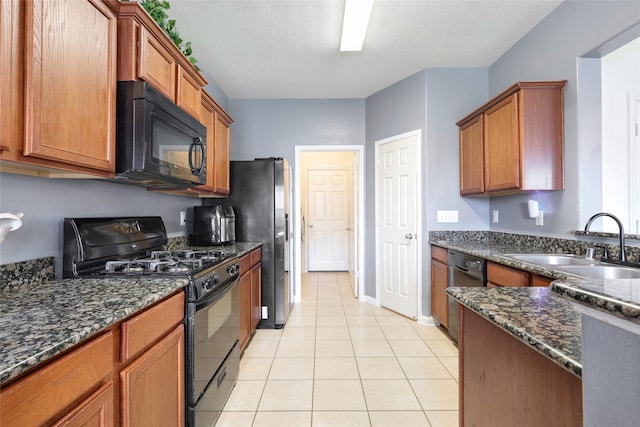 kitchen featuring dark stone counters, black appliances, sink, a textured ceiling, and light tile patterned flooring