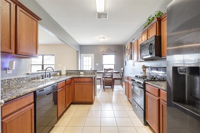 kitchen featuring light tile patterned flooring, sink, dark stone counters, and black appliances