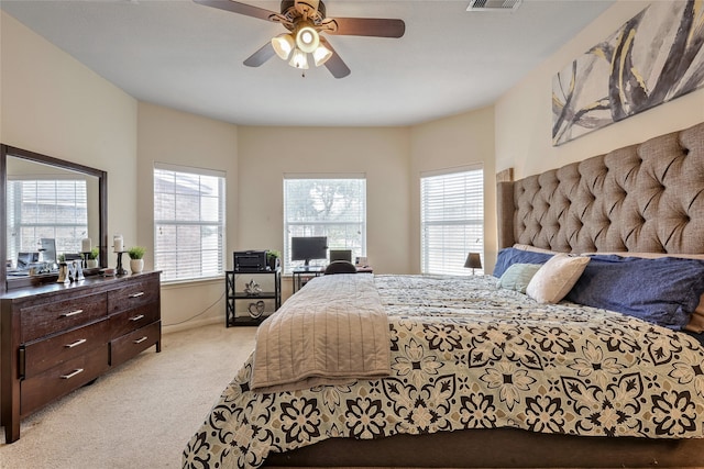 bedroom with light colored carpet, multiple windows, and ceiling fan