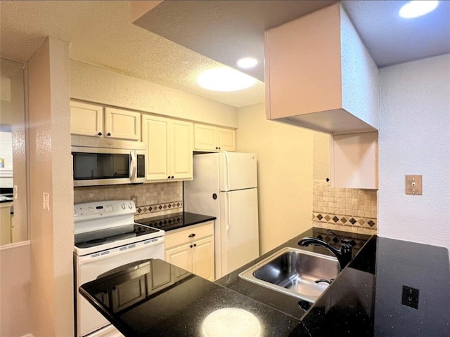 kitchen featuring decorative backsplash, sink, white cabinets, and white appliances