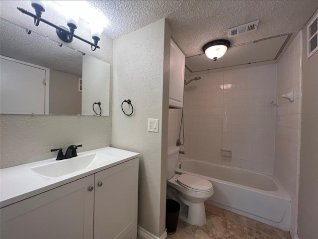 full bathroom featuring a textured ceiling, vanity, toilet, and tiled shower / bath