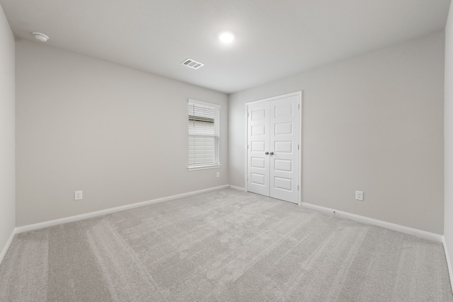 unfurnished bedroom featuring light colored carpet and a closet