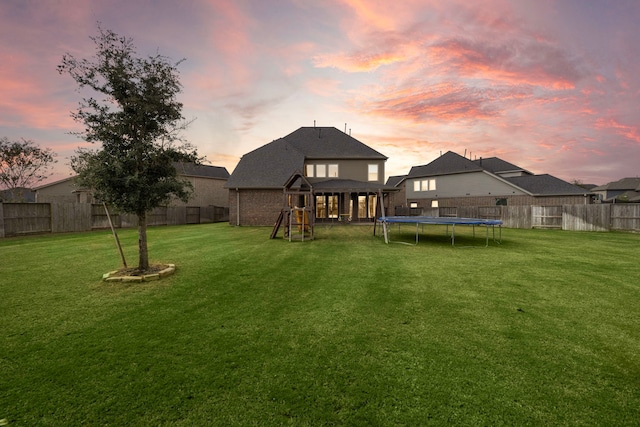 yard at dusk with a playground and a trampoline