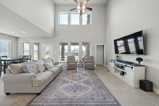 living room featuring ceiling fan, plenty of natural light, and a high ceiling