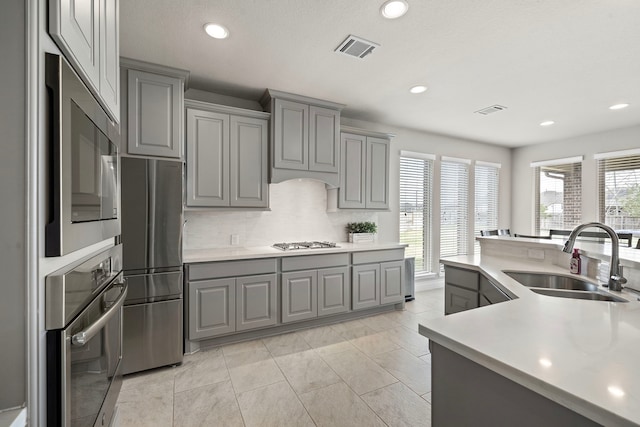 kitchen featuring gray cabinetry, a healthy amount of sunlight, sink, and stainless steel appliances