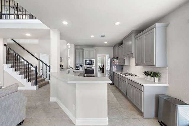 kitchen with backsplash, stainless steel appliances, gray cabinetry, and sink