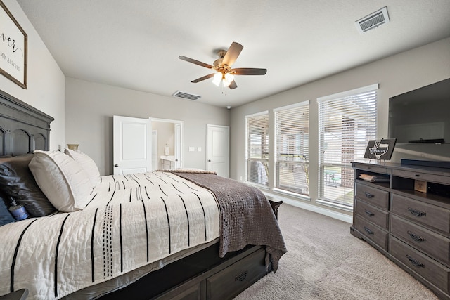 bedroom with ceiling fan, light carpet, and connected bathroom