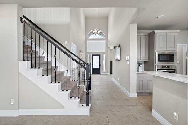 entrance foyer with light tile patterned floors, a high ceiling, and an inviting chandelier