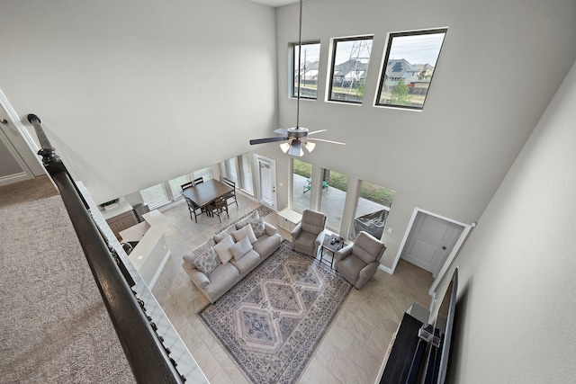 living room with a wealth of natural light, a towering ceiling, and ceiling fan