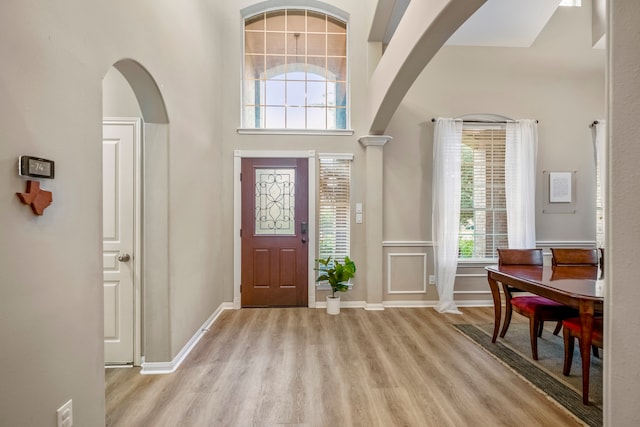 foyer entrance featuring plenty of natural light, light wood-type flooring, and a towering ceiling