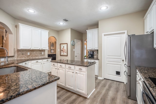 kitchen with sink, light hardwood / wood-style flooring, a textured ceiling, a kitchen island, and white cabinetry