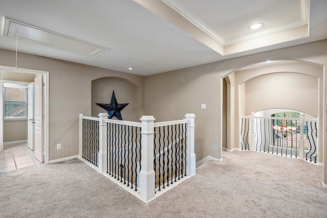 hallway featuring light colored carpet, a raised ceiling, and crown molding