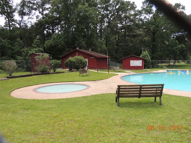 view of pool featuring a lawn and a storage unit