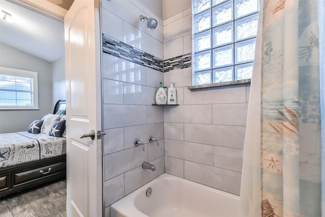 bathroom featuring hardwood / wood-style flooring, vaulted ceiling, and shower / bathtub combination with curtain