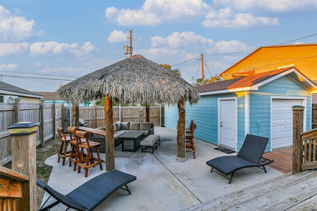 view of patio / terrace featuring outdoor lounge area, a garage, and an outbuilding