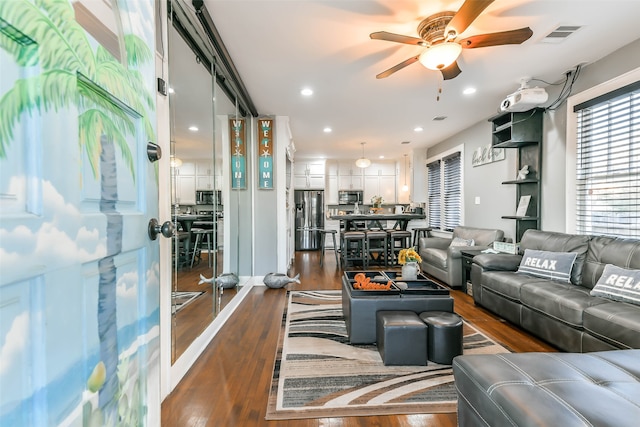 living room featuring ceiling fan and dark wood-type flooring