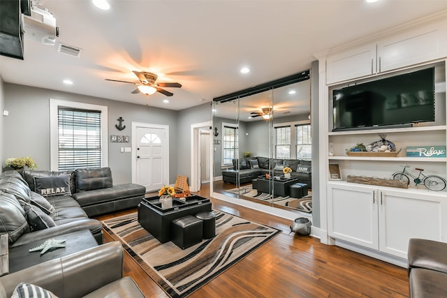 living room featuring a wealth of natural light, ceiling fan, and dark hardwood / wood-style floors