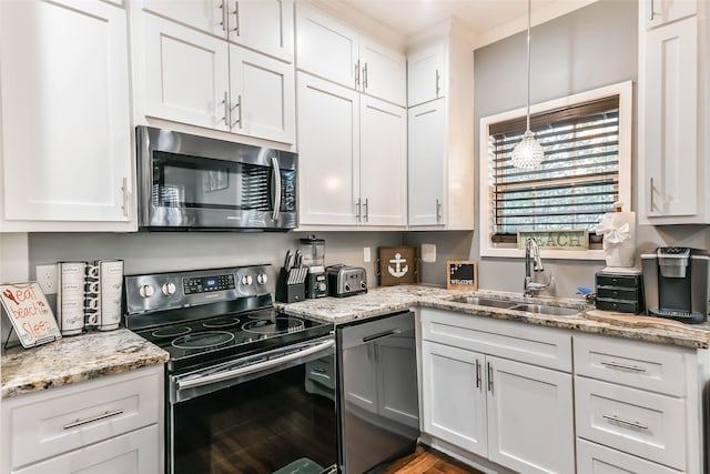 kitchen with light stone countertops, stainless steel appliances, sink, decorative light fixtures, and white cabinetry