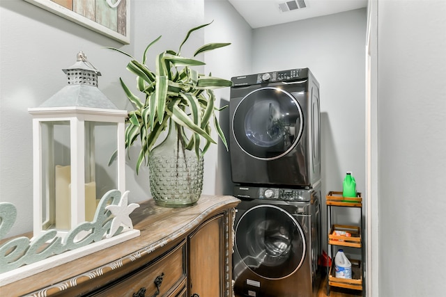 laundry room featuring cabinets and stacked washer and clothes dryer