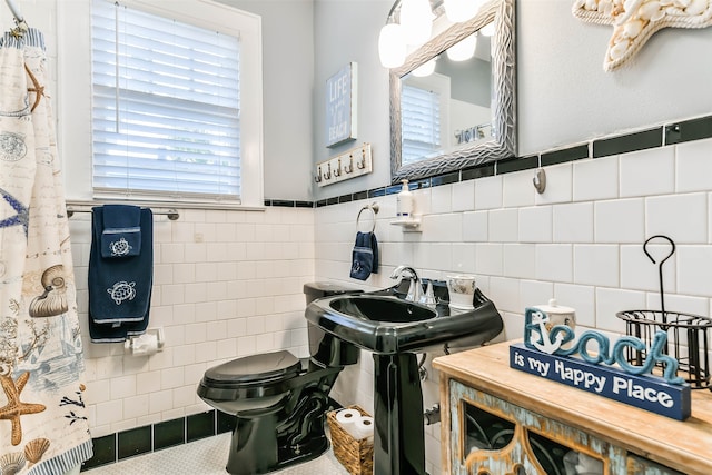 bathroom featuring tile patterned floors, toilet, and tile walls