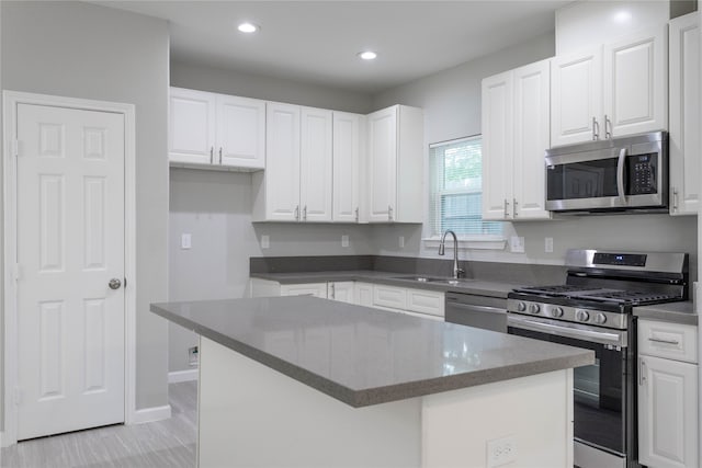 kitchen with appliances with stainless steel finishes, a center island, white cabinetry, and sink