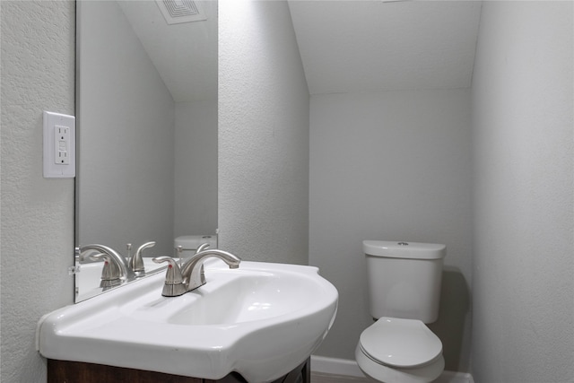 bathroom with sink, vaulted ceiling, and toilet