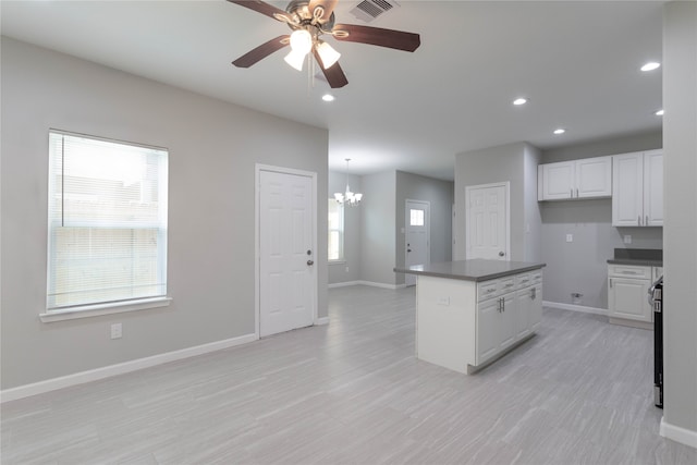 kitchen with white cabinets, ceiling fan with notable chandelier, plenty of natural light, and hanging light fixtures