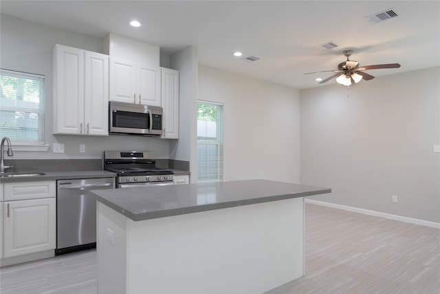 kitchen featuring white cabinets, ceiling fan, light hardwood / wood-style floors, a kitchen island, and stainless steel appliances