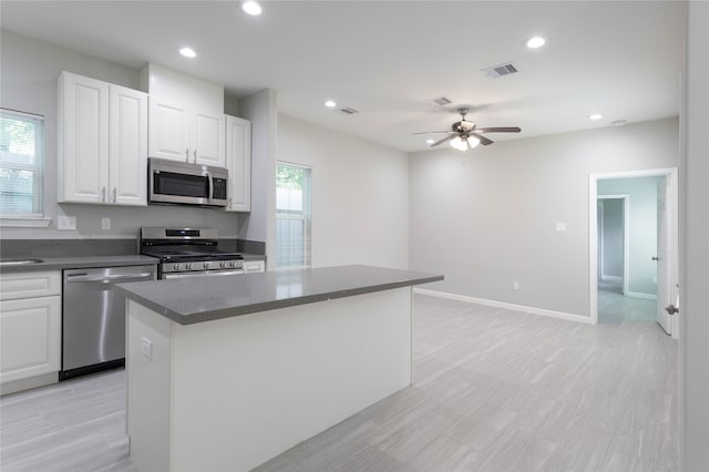 kitchen featuring a center island, stainless steel appliances, white cabinetry, and a wealth of natural light