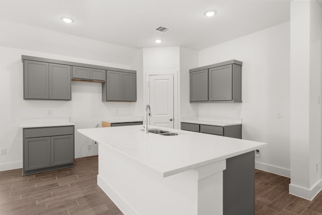 kitchen with gray cabinets, a kitchen island with sink, sink, and dark hardwood / wood-style floors