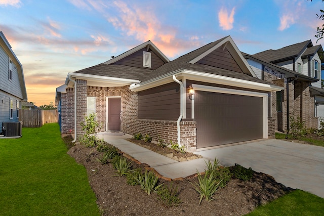 view of front of home with a yard, central AC unit, and a garage