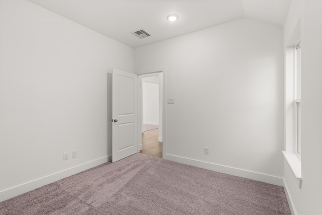 spare room with light colored carpet and vaulted ceiling