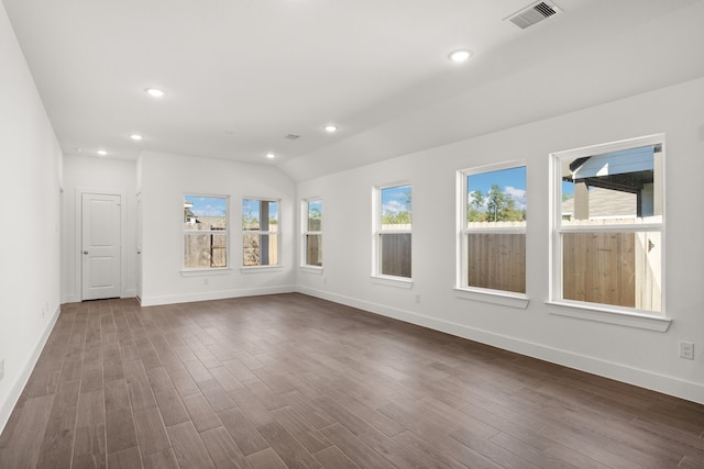 spare room with dark hardwood / wood-style flooring, vaulted ceiling, and plenty of natural light