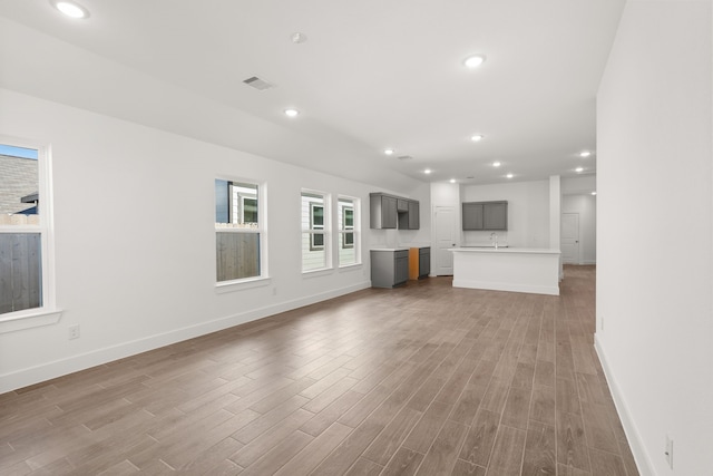 unfurnished living room featuring wood-type flooring and sink